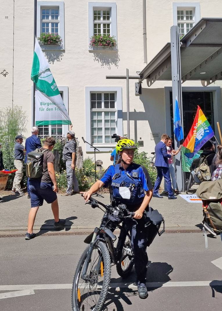 Frauen und Männer und eine Polizistin auf einem Fahrrad vor dem Rathaus in Trier.